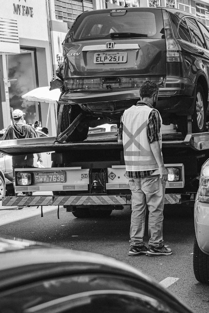 why-choose-us Grayscale image of a tow truck loading a vehicle on a busy street in São Paulo.