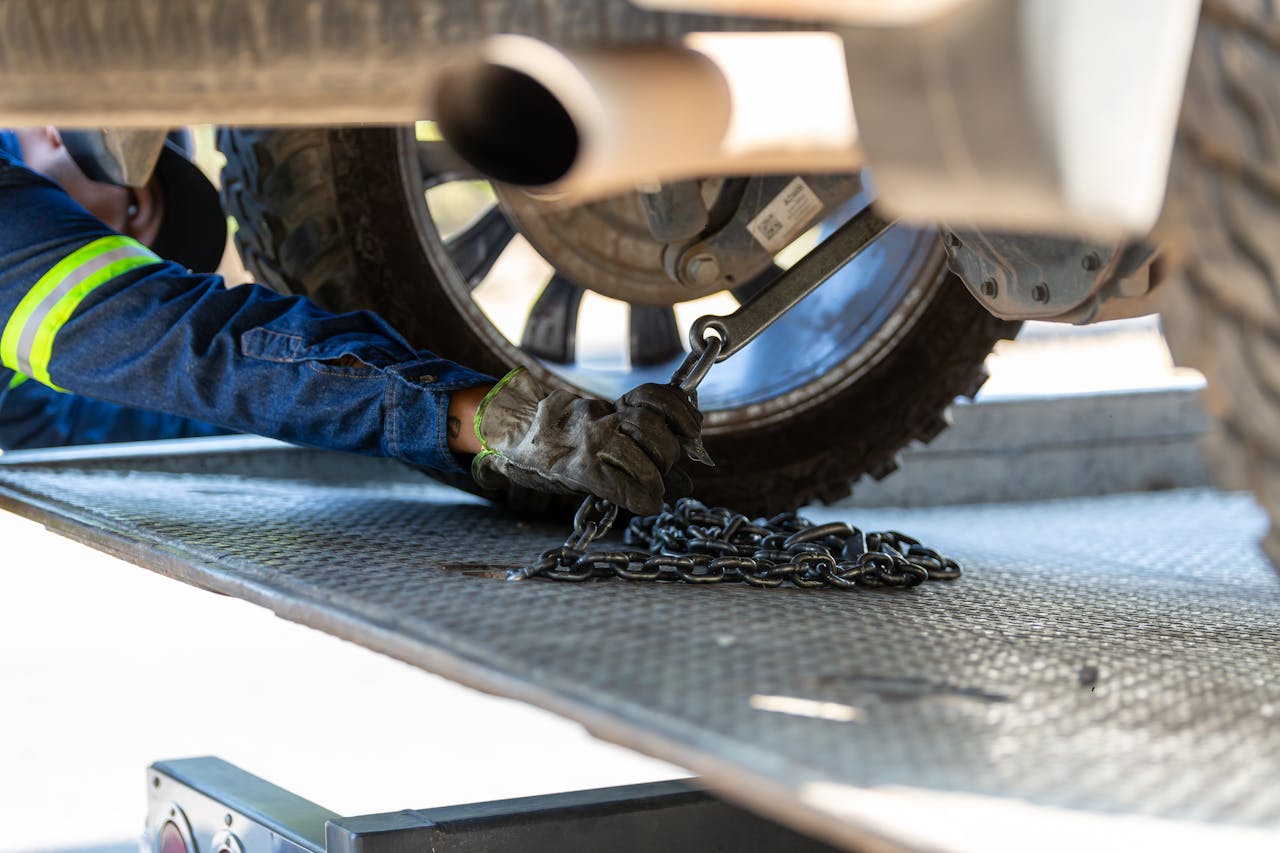 about-02 Mechanic securing a vehicle on a service platform with a chain for safe towing.