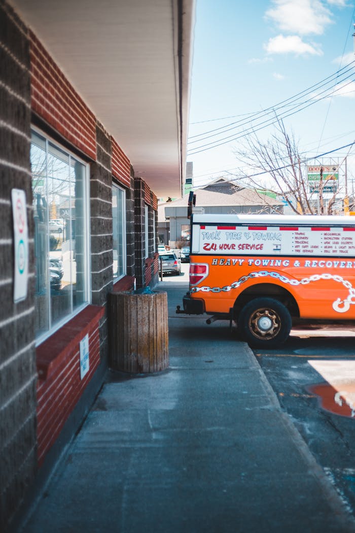 Colorful towing truck parked alongside an industrial building on a sunny day.